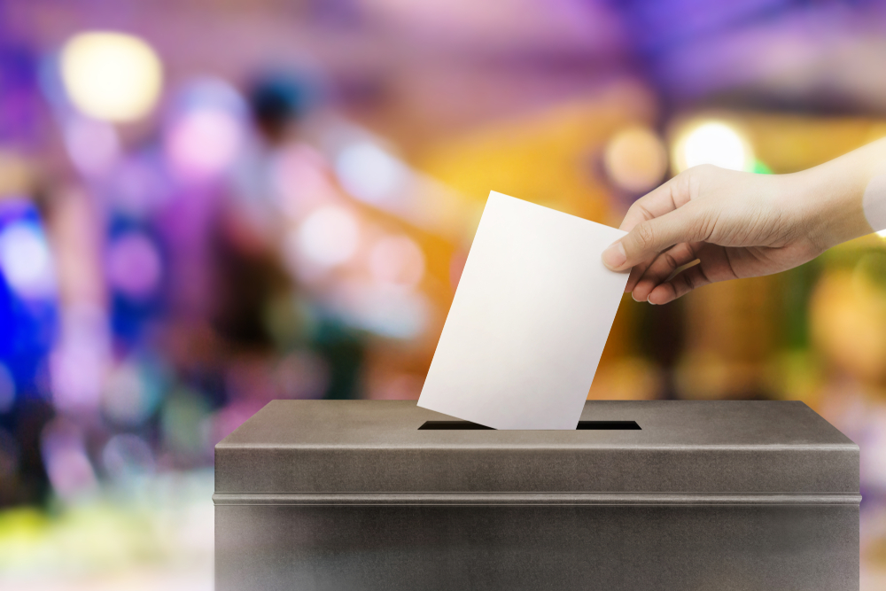 View of woman's hand placing ballot into ballot box.