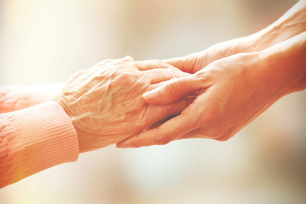 Young woman taking the hands of a senior woman.