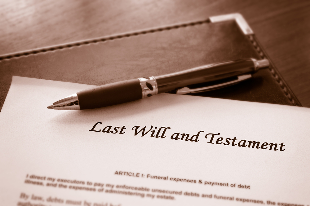 A last will and testament document on a desk with a pen