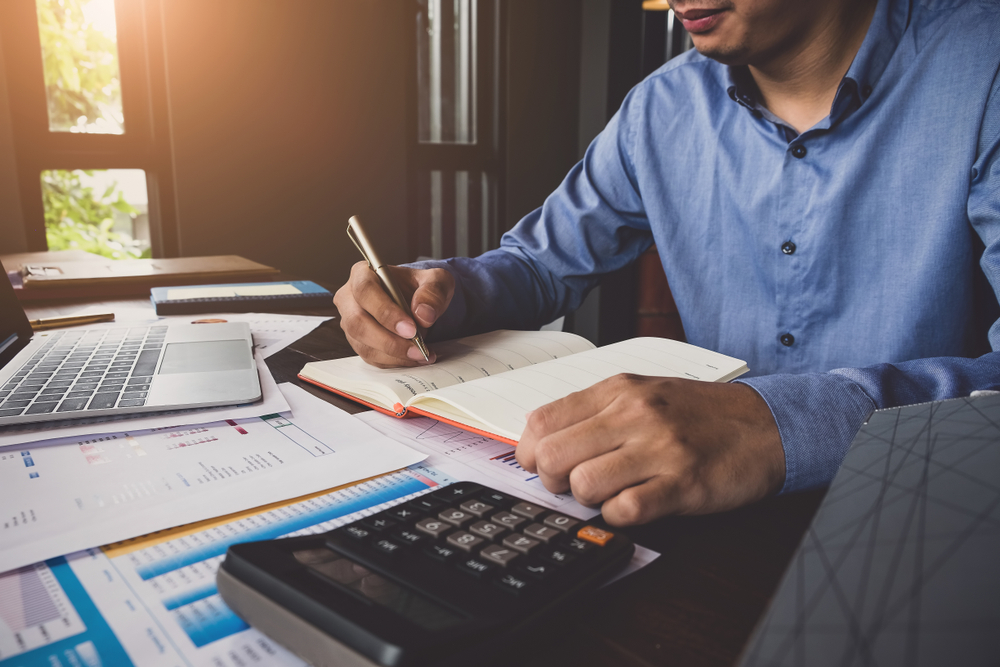 Man sits with calculator and paperwork.