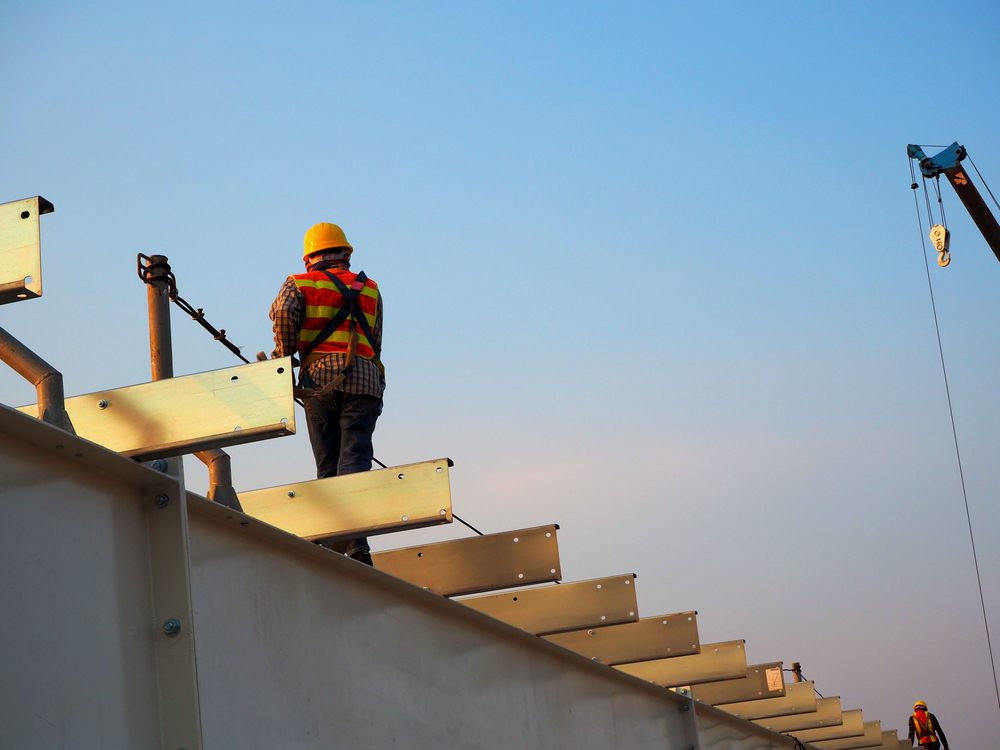 Worker standing on beams of building under construction